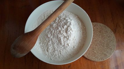 Flour,tremors, salt, sugar, water in a white bowl on a wooden table. Cooking process. Pancakes recipe.	
