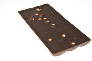 Bar of milk chocolate with raisins and dried apricots on a background of cinnamon sticks close-up
