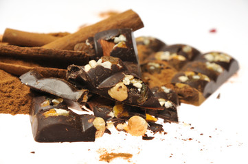 Bar of dark chocolate with raisins and dried apricots on a background of cinnamon sticks close-up