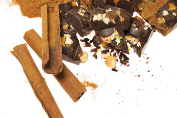 Bar of dark chocolate with raisins and dried apricots on a background of cinnamon sticks close-up