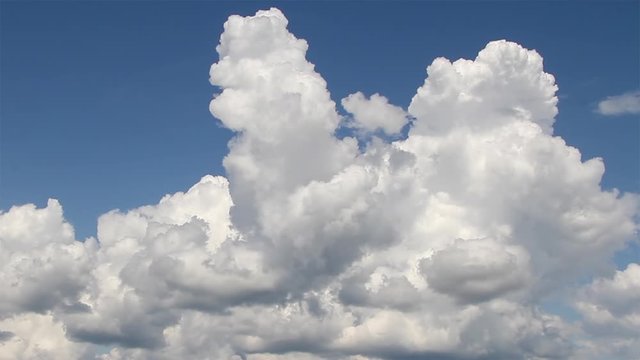 White cumulus clouds motion on the blue sky background. Time Lapse.