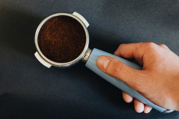Espresso filter holder for coffee machine on Black background in hand