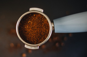 Coffee filter holder with and roasted beans scattered around on black background