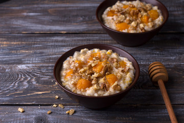 Delicious oatmeal porridge with baked pumpkin, honey and nuts in ceramic bowl on wooden table. healthy homemade breakfast. selective focus, space