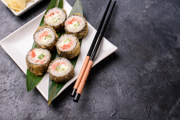 Set hot rolls with avacado, salmon, cream cheese, seaweed, soy sauce, ginger on a dark table. Sushi