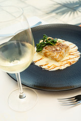 Plate of cod cream with spinach and glass of white wine
