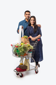 Happy Indian couple with a shopping cart. Isolated over white background