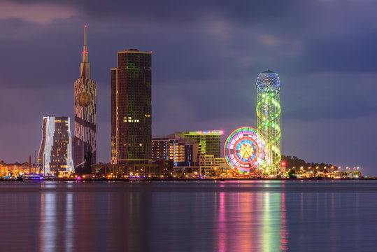 Batumi, Adjara, Georgia - September 20, 2017: Scene Of Resort Town with skyscrapers at night. View From Sea Beach To Illuminated Cityscape With Modern Urban Architecture, Skyscrapers And Tower. 