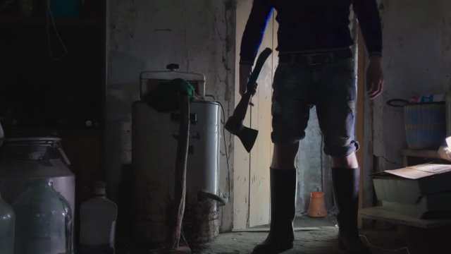 A man with an axe standing in a dark room. copy space