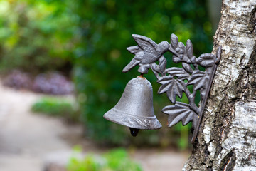 Metal doorbell hanged on the tree in the garden 