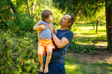 Portrait of baby boy with Down syndrome playing with dad in summer day on nature