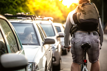 An unidentified man riding a bicycle passing cars on the road in the traffic