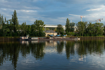 reflection of boats in the water with cranes behind