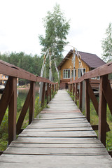 wooden bridge leads to a house on forest lake