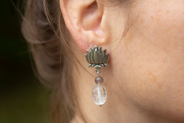 Closeup of lotus shape crystal quartz earring on female ear