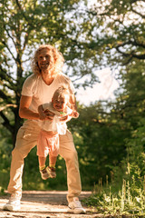 Fototapeta premium Father and daughter playing on the grass at the day time. Concept of friendly family.