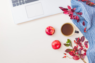 Flat lay home office desktop with colorful autumn leaves, laptop and a cup of coffee on a white background