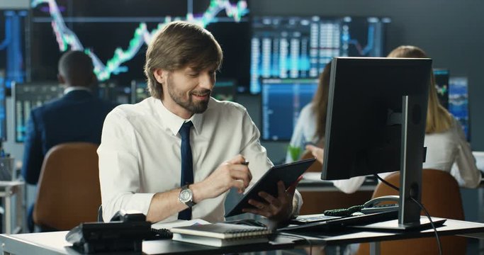 Caucasian handsome young man broker working at computer in trading office. Male manager typing on keyboard. Trader putting bets and rates on stock markt online. Following trends.