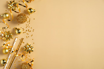 Christmas party invitation card mockup. Flat lay golden Christmas balls, decorations, tinsel, confetti on yellow background. Top view with copy space.