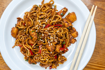 Delicious Spicy chicken Chinese egg noodles served on a white plate with table wood background / Asian food 