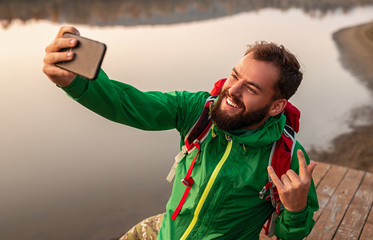 Naklejka premium Happy bearded traveler taking selfie on pier