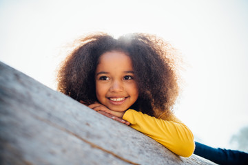 portrait of a young African American girl resting on log