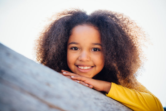 portrait of a young African American girl resting on log