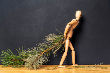 Wooden man carries a Christmas tree branch