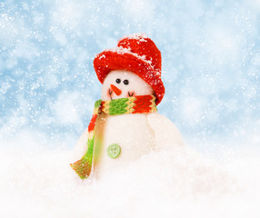 Cheerful snowman in a red cap on the snow.