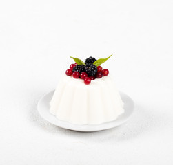 Dessert cream pudding with fresh berries on a plate on a white background