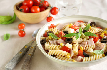 Concetto di cibo italiano. Insalata di pasta con mozzarella, pomodori prosciutto e olive sul...
