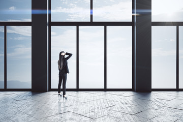Fototapeta premium Thoughtful businesswomen standing in empty concrete hallway interior.