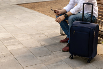 Man in casual clothes sitting on a bench with a suitcase