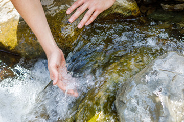 Hand is in a mountain river stream.