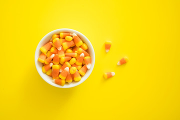 Colorful Candy Corn in a Bowl on a Yellow Background with Room for Copy