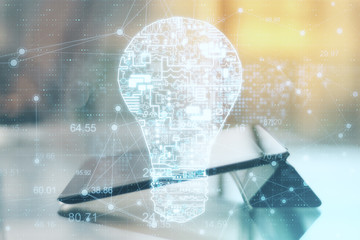 Digital tablet with glowing circuit light bulb hologram.