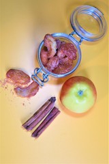 Homemade dried organic apple sliced with cinnamon in a jar l and pieces of this fruits on a table.