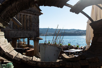 Dry plant in a metallic pot on top of an ancient fishing tool with an old house uses as storage for fishers in Galicia, Spain, in the backgroundg