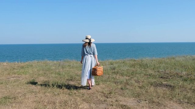 Romantic Fashion Woman in Vintage Dress Walking on Precipice of Hill above the Sea. Slow motion
