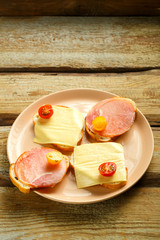 Sandwiches with ham and cheese and cherry on a plate on a wooden table. Copy the place.