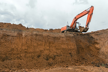 Obraz premium The construction site excavator digs a deep pit. Digger. Construction machinery. Excavation at a construction site
