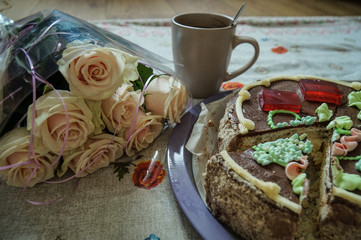 Bouquet of cream roses, Kiev cake and a cup on the table.  