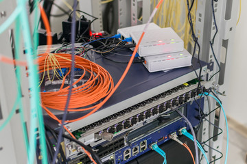 Telecommunication equipment works in the data center rack. There are many fiber optic cables in the server room. Selective focus