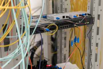 There are many fiber optic cables in the server room. Telecommunication equipment works in the data center rack. Selective focus