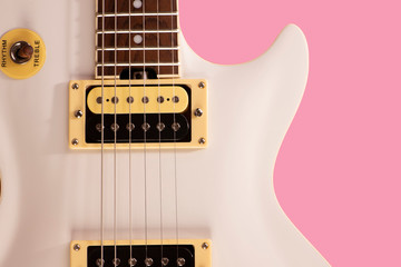 front part of the body of a white electric guitar on pink background