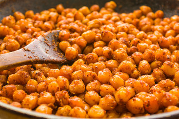 Cooking chickpeas with spices in a pan, close-up