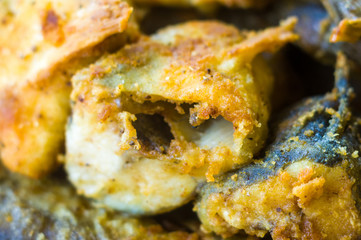 Pieces of navaga fish in batter, fried in oil in a pan.