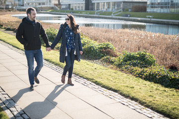 A young couple holding hands while talking and walking near a canal in the city of Edinburgh, Scotland, United Kingdom