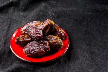 Big luxury dried date fruit in bowls on the dark surface, kurma ramadan kareem concept, close up.