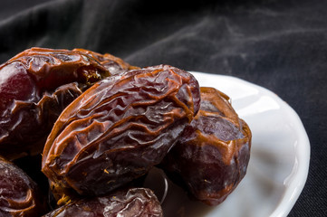 Big luxury dried date fruit in bowls on the dark surface, kurma ramadan kareem concept, close up.